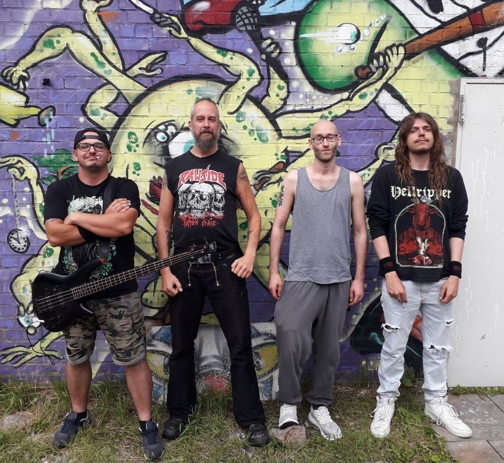 Vier Personen vor einer mit Graffiti bemalten Mauer.